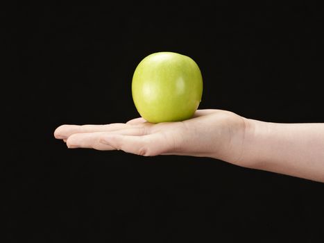 Childs hand with apple in palm - on black background