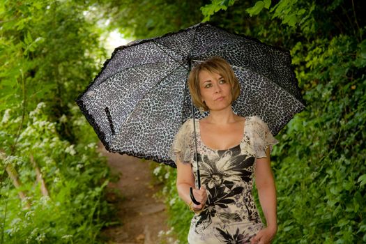 outdoor photo of a woman walking carrying an umbrella