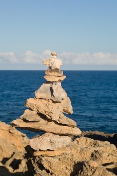 Pyramid shaped stack of rocks balanced on the edge of ocean