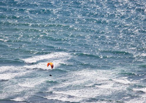 Overhead view of hang glider over rough ocean off Hawaii