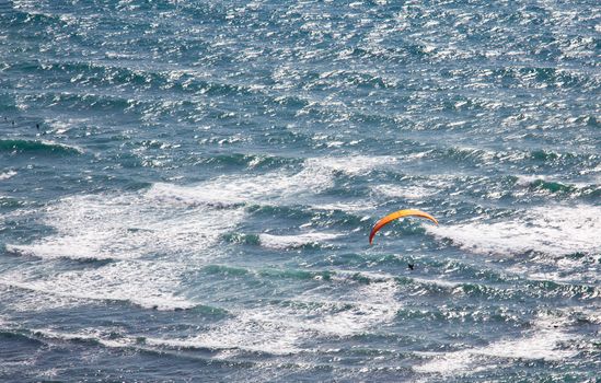 Overhead view of hang glider over rough ocean off Hawaii