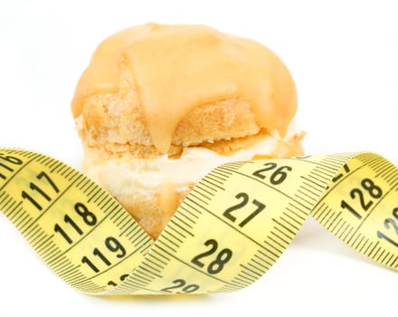 concept of slimming, caramel cake with measuring tape on white background