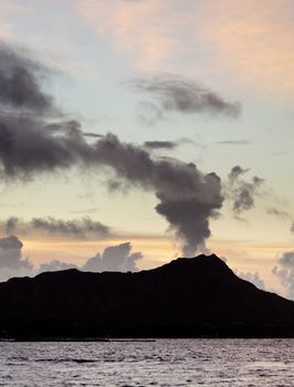 Clouds appear to be smoke from volcano of Diamond Head at sunrise in Hawaii