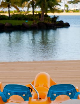 Orange and blue pedal boats on sand by ocean