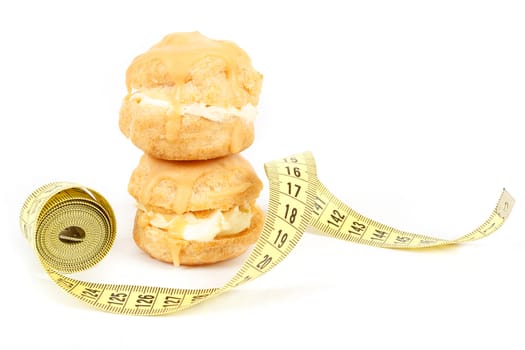 concept of slimming, caramel cakes with measuring tape on white background