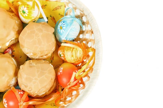 easter eggs and homemade sweet cakes in basket on white