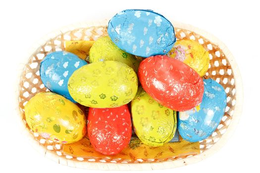 easter chocolate eggs in a basket isolated on white