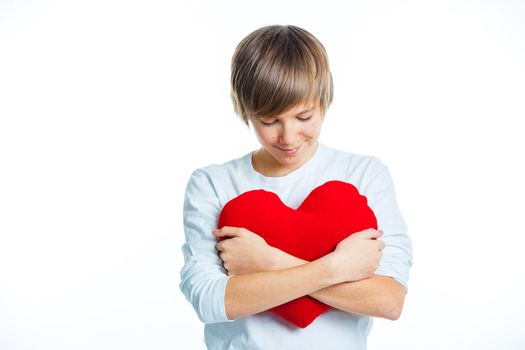 A cute young boy in love with a red plush heart in his hands. isolated