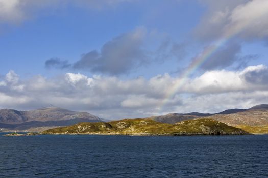 coastal scene in scotland with rainbow over hills