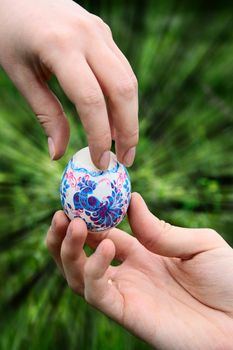 male hand giving easter color egg to woman hand