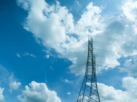 transmission tower against dramatic blue sky with clouds.