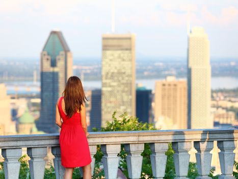 Montreal. Woman looking at Montreal downtown skyline cityscape. Tourist girl in red dress on Mont Royal in spring or summer.