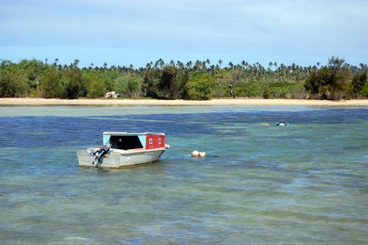 Motor boat near sandy coast with palms, South Pacific, Tonga