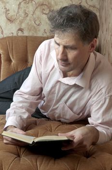 Portrait of middle-aged man reading a book in the black cover at home