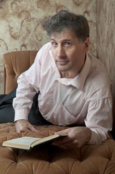 Portrait of middle-aged man reading a book in the black cover at home