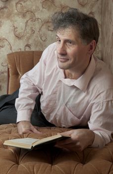 Portrait of middle-aged man reading a book in the black cover at home