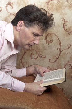 Portrait of middle-aged man reading a book in the black cover at home