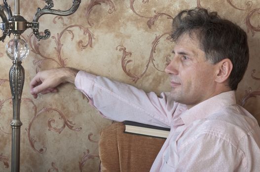 Portrait of middle-aged man reading a book in the black cover at home