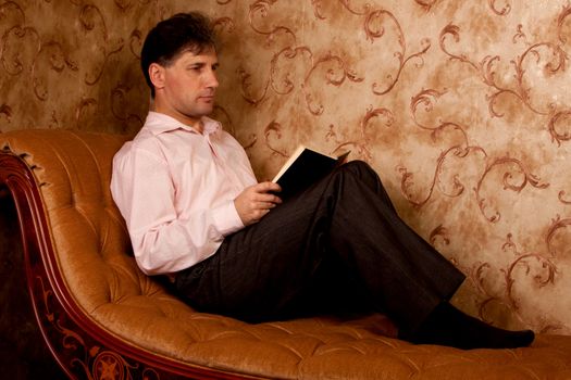 Portrait of middle-aged man reading a book in the black cover at home