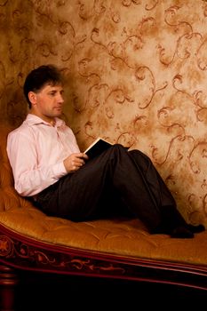 Portrait of middle-aged man reading a book in the black cover at home