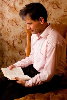 Portrait of middle-aged man reading a book in the black cover at home