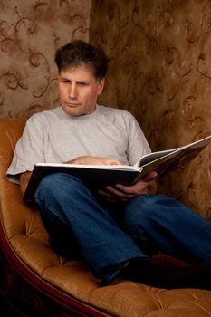 Portrait of middle-aged man reading a book in the black cover at home