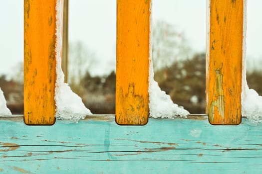 Snow clumps on a colorful wooden set of railings