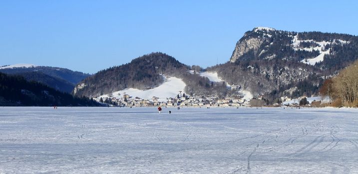 Panoramic view on the frozen lake of the Joux valley and Le Pont village by winter day, Vaud canton, Switzerland