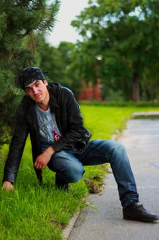 A handsome man in a bandana and a leather jacket in black with a hand from a person in joyful meditations