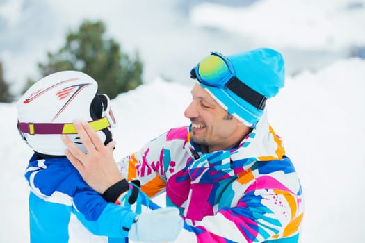 portrait closeup of happy and smiling father and son in ski goggles and a helmet