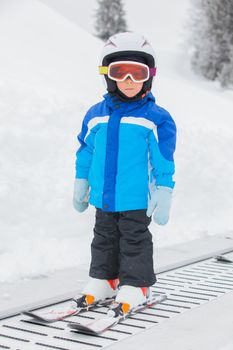 Junior skier in the ski school. Little cute boy in a ski equipment on lift on hill