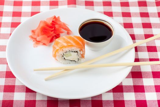 Sushi, soy and ginger with chopsticks on a white plate