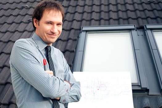 young man architect presenting a project against the background of the roof and windows