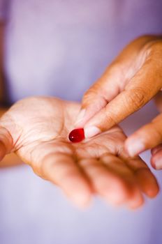 a close up of on medicine on palm, woman is taking medicine.