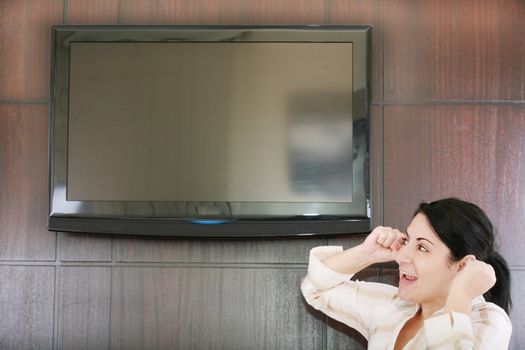 Rear view of excited soccer fan standing up and watching favorite team goal at tv