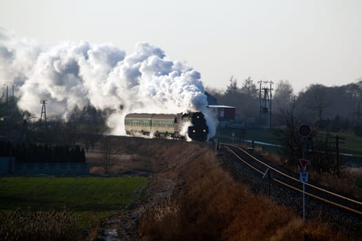 Vintage steam train passing through countryside, wintertime
