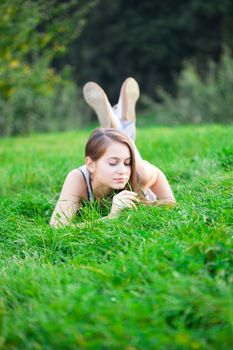 beautiful young woman lying on green grass