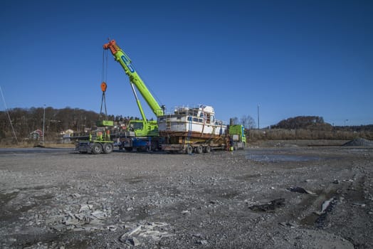 The boat was transported by trailer and was unloaded with a huge mobile crane on the quay at the port of Halden, Norway. The picture is shot one day in March.