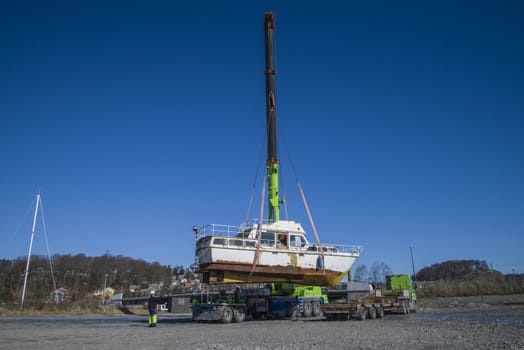 The boat was transported by trailer and was unloaded with a huge mobile crane on the quay at the port of Halden, Norway. The picture is shot one day in March.