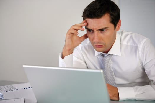 Businessman getting stressed at laptop