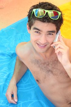 Young man lying on the beach with a cellphone