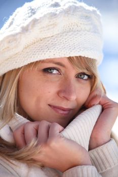 Blonde woman in a cream jumper and hat