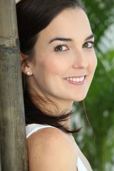 Close up of a woman's face next to a large bamboo