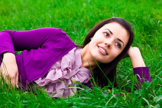 beautiful young woman lying on green grass
