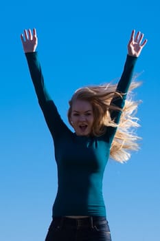 young beautiful woman jumping into the field against the sky