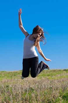 young beautiful woman jumping into the field against the sky