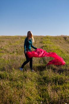 young beautiful woman jumping with tissue into the field against the sky