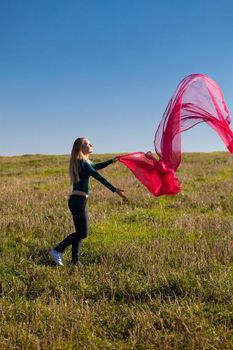 young beautiful woman jumping with tissue into the field against the sky