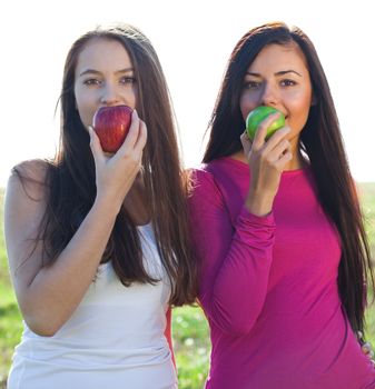 portret of two young beautiful woman with apple on the  sky background 