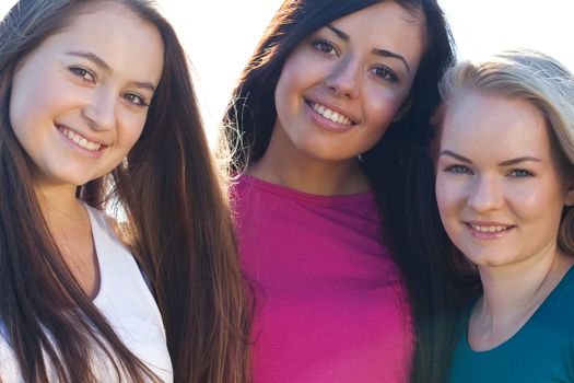 portret of three young beautiful woman on the  sky background 